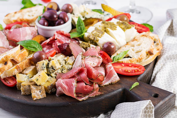 Antipasto platter with ham, prosciutto, salami, blue cheese, mozzarella with pesto and olives on a wooden background. stock photo