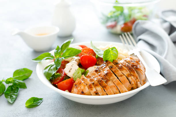 grillowana miska na lunch z kurczaka z sosem pomarańczowym, sałatką z makaronu i kaparu - caprese salad zdjęcia i obrazy z banku zdjęć