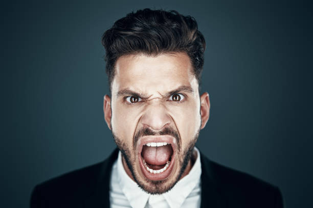 istock Angry young man making a face and looking at camera while standing against grey background 1167968020