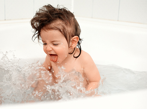 Cute little girl splashing water in the bathtub