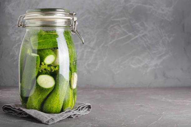 istock Pickling and fermentation cucumber in glass jar with dill and garlic on grey table. 1167969515