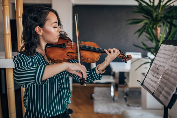 istock Young woman violinist playing violin at home 1167969901