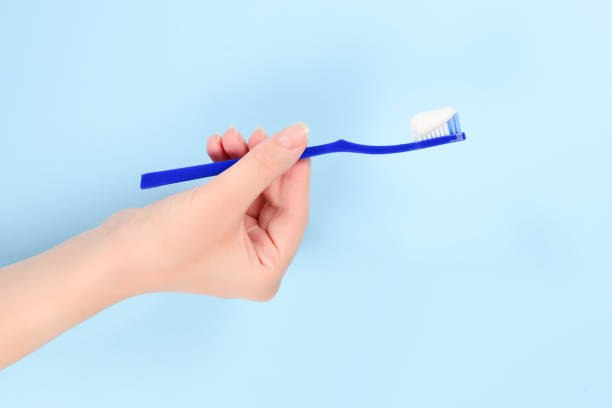 istock Woman holds toothbrush with toothpaste in her hand on a blue background. 1167970228