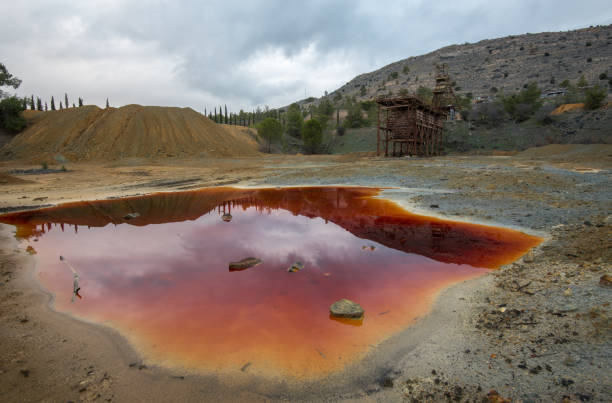 Abandoned copper mine in Cyprus Abandoned copper mine with red toxic water and dramatic stormy cloudy sky at Mitsero area in Cyprus land mine stock pictures, royalty-free photos & images
