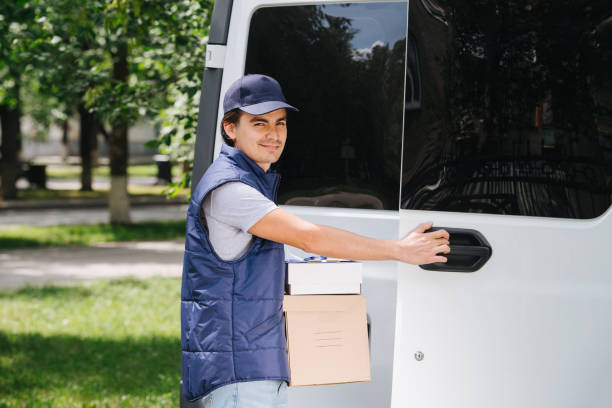 istock Delivery man in uniform is holding parcel cardboard boxes next to his car 1167970958
