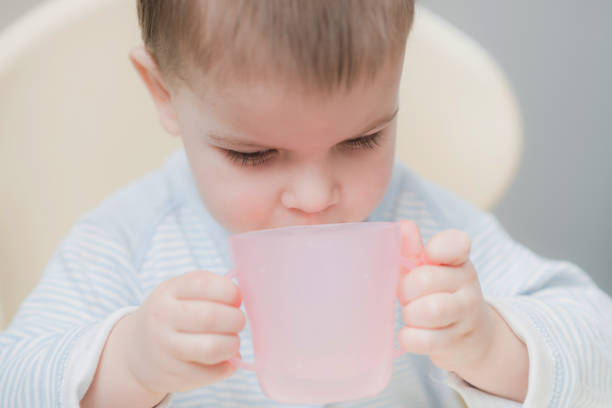the child in the kitchen drinks water