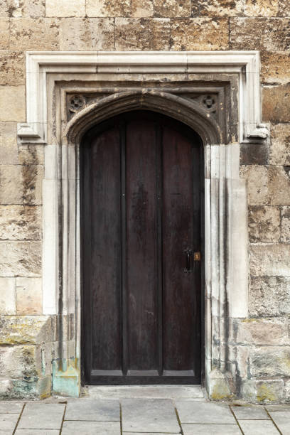 istock Closed black wooden door in old stone wall 1167971908