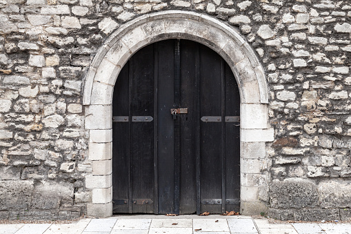 Closed black wooden door in old stone wall, background photo texture