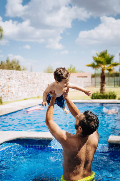 istock Latin father playing with toddler in swimming pool 1167973143