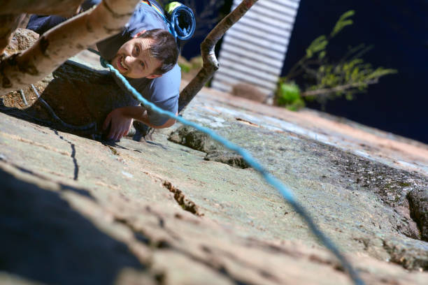 女性のロッククライマーは岩の壁に登る。上からの眺め - climbing wall rock climbing holding reaching ストックフォトと画像