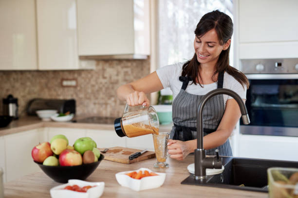 istock Woman pouring smoothie into a glass. 1167973850