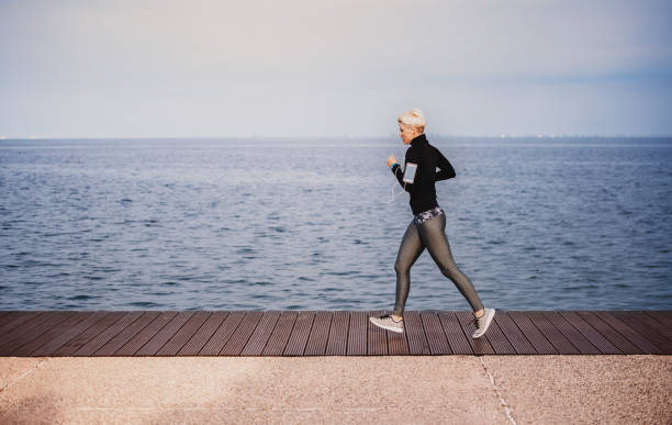 istock Side view of young sportswoman running outdoors on beach. 1167976562