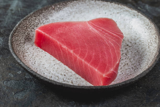 tonno fresco crudo stek su piatto grigio. sfondo nero - tuna steak fillet food plate foto e immagini stock
