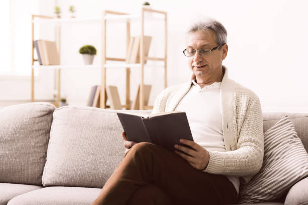 istock Happy pensioner reading book, having rest on sofa 1167980428