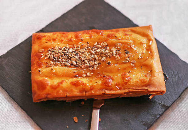 traditional greek cheese called feta - wrapped in phyllo crust - with honey, sesame and nuts stock photo