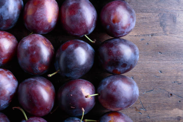 istock Ripe juicy plums on a wooden background. 1167985520