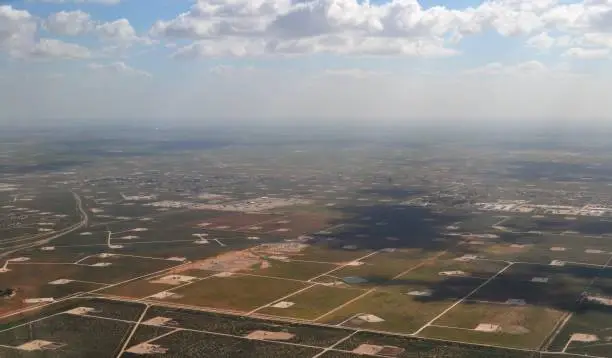 A birds eye view of the thousands of pumps, drills, and oil rigs connected by strings of dirt roads in the Permian Basin in Western Texas. An amazing sight with the clouds casting giant shadows and the bluest of skies above them.