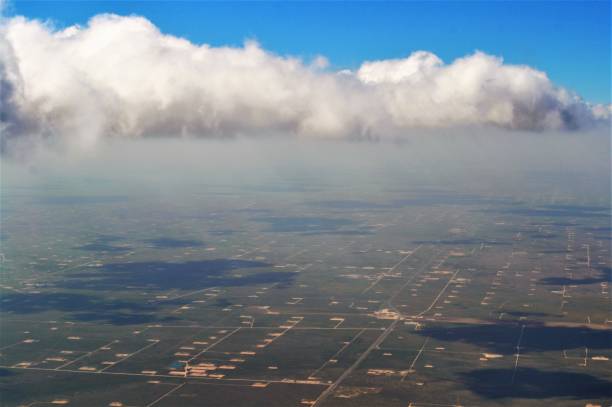 West Texas Oil Fields in the Permian Basin A birds eye view of the thousands of pumps, drills, and oil rigs connected by strings of dirt roads in the Permian Basin in Western Texas. An amazing sight with the clouds casting giant shadows and the bluest of skies above them. wellhead stock pictures, royalty-free photos & images