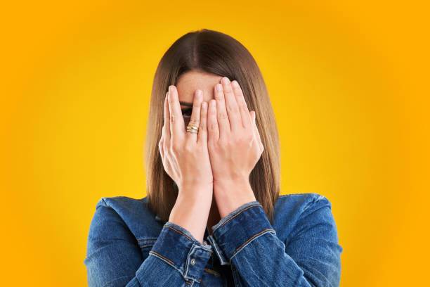donna infelice in giacca di denim su sfondo giallo - hands covering eyes foto e immagini stock