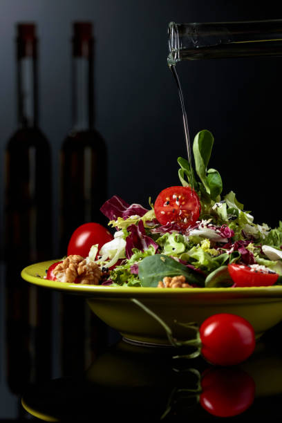 istock Green salad with cherry tomatoes, sesame and walnuts watered with vegetable oil. 1167988055
