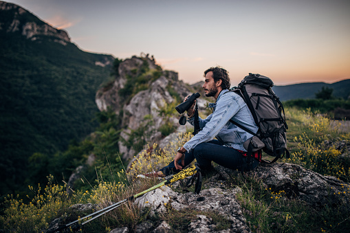 Young handsome hiker watching landskape with his binoculars