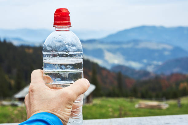 istock mans hand holding plastic bottle with clean water on the mountains background 1167992600