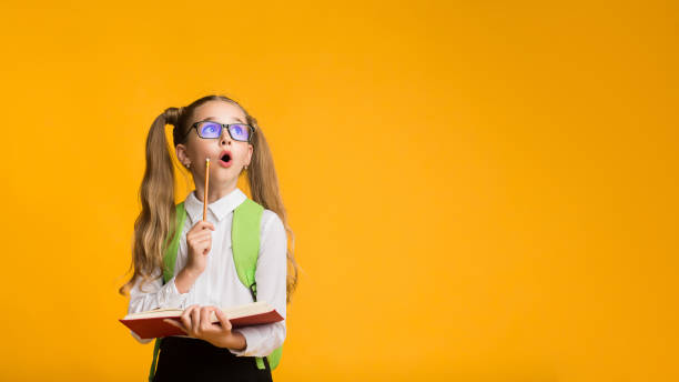 istock Curious First-Grade Schoolgirl Holding Opened Book And Pencil 1167994047