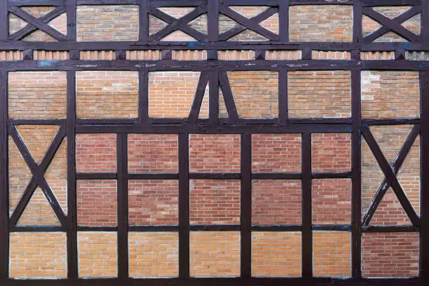 Old wall made of brown half-timbered, bricked with bricks in different shades