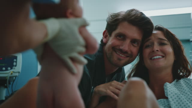 Couple smiling and looking at newborn in hospital