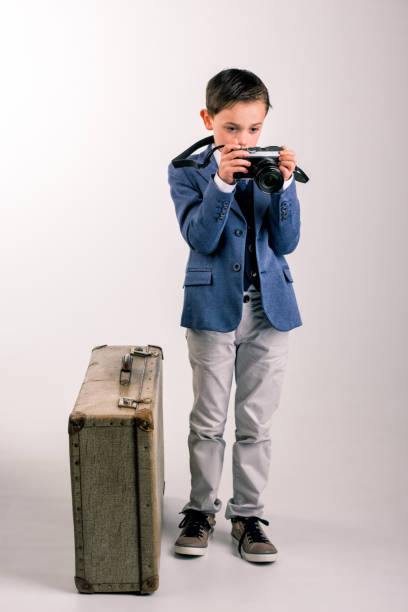 istock Young boy dressed up with photo camera and suitcase 1167998887