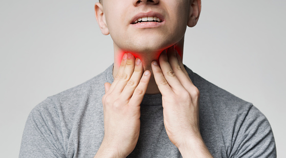 Breathing problem. Young man pulping his inflamed neck, close up