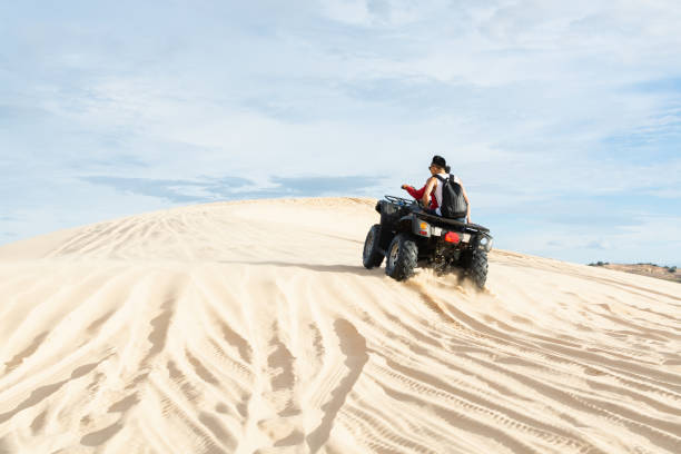 Of-road ATV quad bike driving through desert sand dunes at sunrise in Mui Ne, Vietnam stock photo