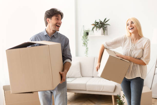 istock Couple Talking Joyfully Carrying Moving Boxes Into New Apartment 1168001511