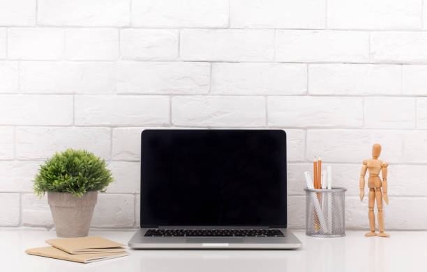istock Laptop with black blank screen on modern white office table 1168001584