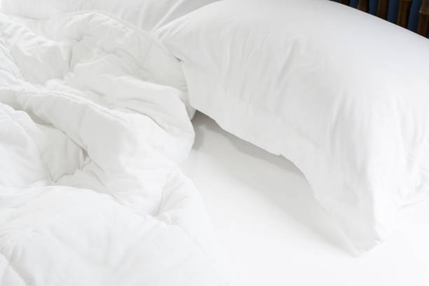 istock Close up messy white sheet and pillows on bed bedroom interior 1168001689