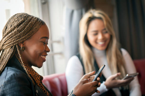 istock Two happy young women using mobile phones in a bar 1168002543