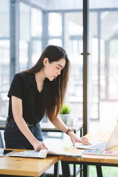 Young Asian graphic designer working on computor and graphics tablet in her working space stock photo