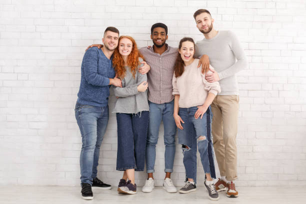 istock Happy friends embracing and posing to camera over white wall 1168002842