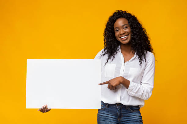 afro chica está sosteniendo tablero de publicidad amarillo - people holding one person sign fotografías e imágenes de stock