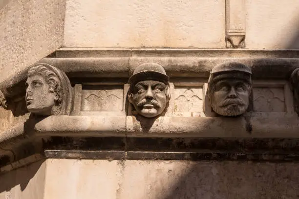 Building made of stone. Walls outdoors enlighted by sunlight, decored with the sculptures of human heads (unknown models). St. James Cathedral, Sibenik, Croatia.