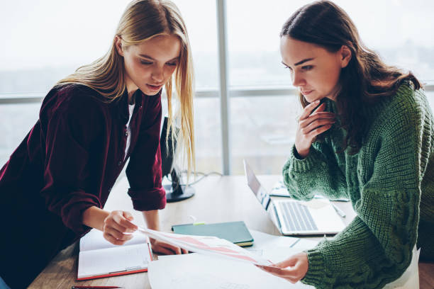 istock Serious two female colleagues analyzing information from report cooperating during woking process in office, skilled women checking accountings while planning statement for startup and research 1168010656