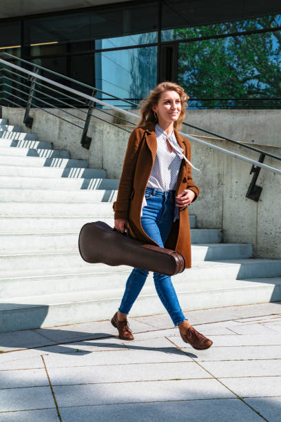 istock Girl with violin in case came down stairs 1168014000