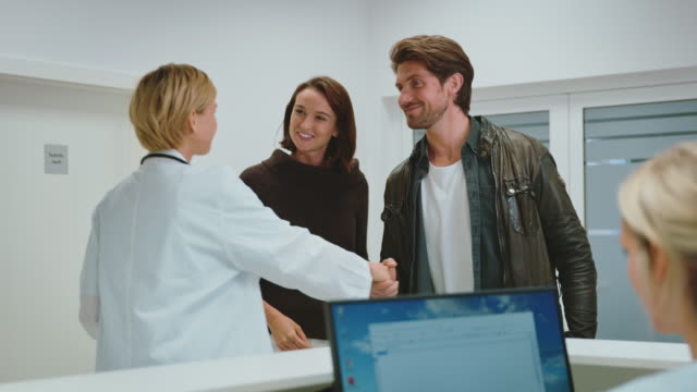 Doctor with young couple at reception desk