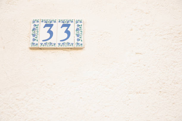 istock Number 33 street address tile on old wall. 1168016334