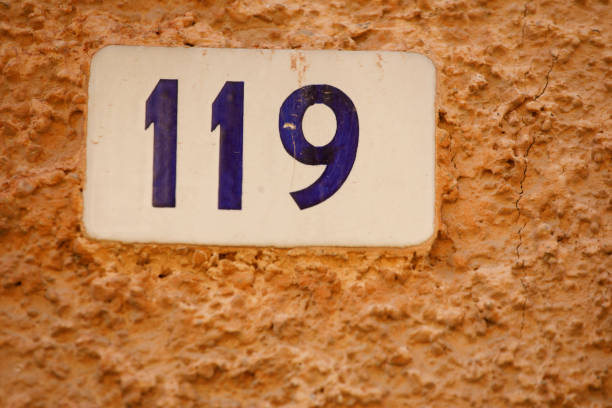 Number 119 street address tile on old wall.