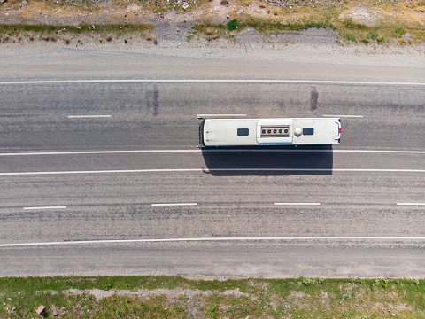 Aerial view of a bus on a high-speed road, with two lanes in each direction. Bus with a white roof. Transportation of people, travel, holidays and tourist destinations. Turkey