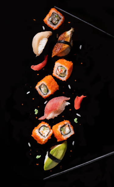 Sushi pieces between chopsticks, flying separated on black background. Sushi pieces between chopsticks, flying separated on black background. chopsticks photos stock pictures, royalty-free photos & images
