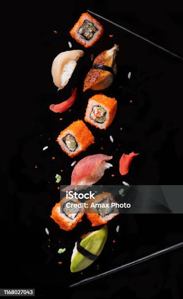 Sushi Pieces Between Chopsticks Flying Separated On Black Background Stock Photo - Download Image Now