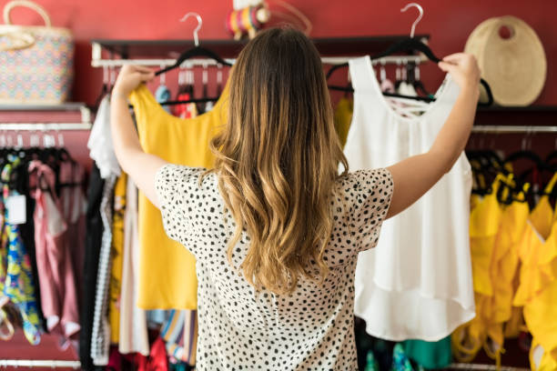 dama caucásica sosteniendo en prendas de vestir en boutique - fashion store fotografías e imágenes de stock