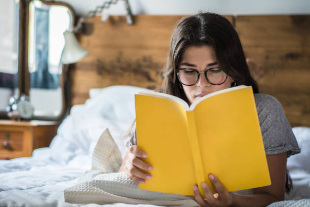 istock woman laying in bed and reading book 1168028702